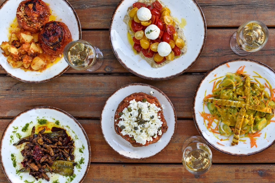 view from above of plates with cooked foods like stuffed tomatoes or fried pumpkins from 'The Orchard in Vari' restaurant